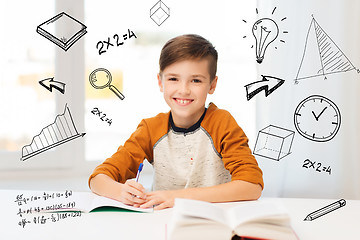 Image showing smiling student boy writing to notebook at home