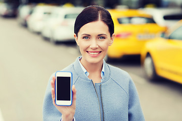 Image showing smiling woman showing smartphone over taxi in city