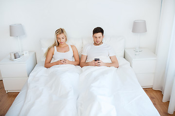 Image showing couple with smartphones in bed