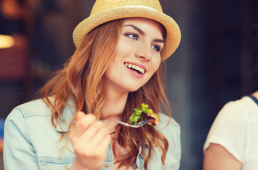 Image showing happy young woman eating salad at bar or pub