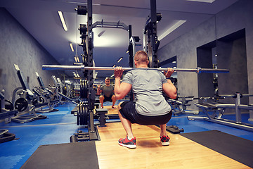 Image showing young man flexing muscles with bar in gym