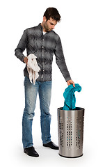 Image showing Young man putting a dirty towel in a laundry basket