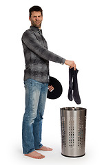 Image showing Young man putting dirty socks in a laundry basket