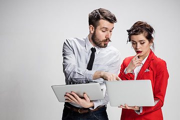 Image showing The young businessman and businesswoman with laptops  communicating on gray background