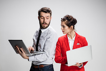 Image showing The young businessman and businesswoman with laptops  communicating on gray background