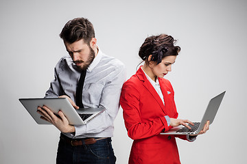 Image showing The young businessman and businesswoman with laptops  communicating on gray background