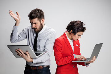 Image showing The young businessman and businesswoman with laptops  communicating on gray background