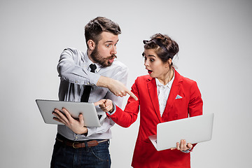 Image showing The young businessman and businesswoman with laptops  communicating on gray background