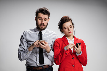 Image showing Business concept. The two young colleagues holding mobile phones on gray background