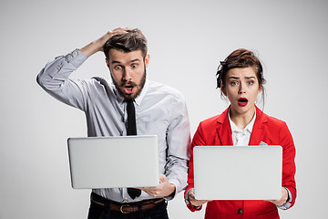 Image showing The young businessman and businesswoman with laptops  communicating on gray background