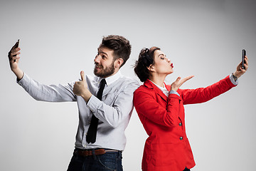 Image showing Business concept. The two young colleagues holding mobile phones on gray background