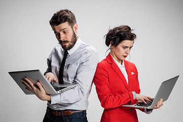 Image showing The young businessman and businesswoman with laptops  communicating on gray background