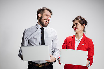 Image showing The young businessman and businesswoman with laptops  communicating on gray background