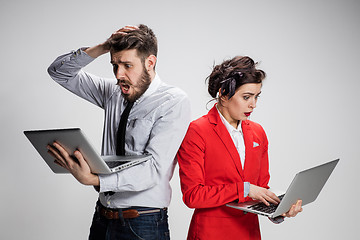 Image showing The young businessman and businesswoman with laptops  communicating on gray background