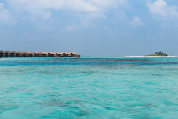 Image showing bungalow huts in sea water on exotic resort beach