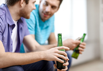 Image showing close up of male friends drinking beer at home