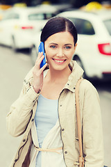 Image showing smiling woman with smartphone over taxi in city