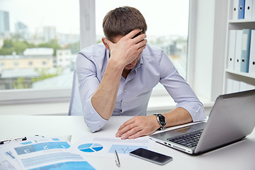 Image showing stressed businessman with papers in office