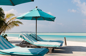 Image showing parasol and sunbeds by sea on maldives beach