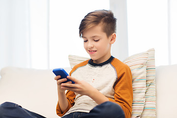 Image showing boy with smartphone texting or playing at home