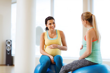 Image showing two happy pregnant women sitting on balls in gym