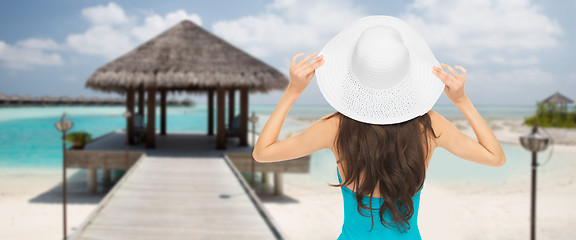 Image showing woman in swimsuit and sun hat from back on beach