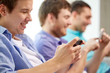 Image showing close up of happy friends with smartphones at home