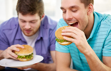 Image showing close up of friends eating hamburgers at home