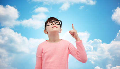 Image showing happy little girl in eyeglasses pointing finger up