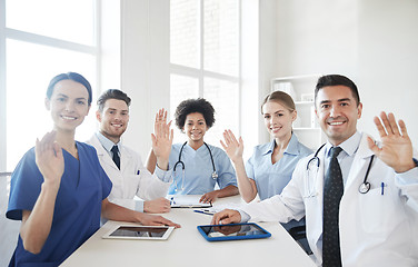 Image showing happy doctors meeting and waving hands at hospital