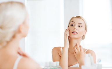 Image showing happy young woman looking to mirror at bathroom