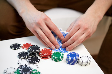 Image showing close up of male hand with playing cards and chips