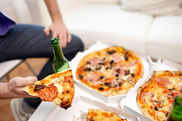 Image showing close up of man eating pizza with beer at home