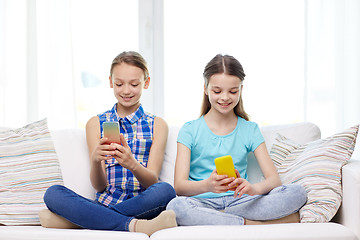 Image showing happy girls with smartphones sitting on sofa