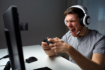 Image showing man in headset playing computer video game at home