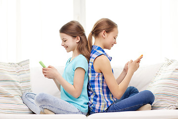 Image showing happy girls with smartphones sitting on sofa