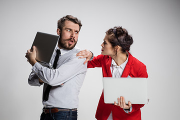 Image showing The young businessman and businesswoman with laptops  communicating on gray background