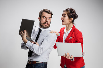 Image showing The young businessman and businesswoman with laptops  communicating on gray background