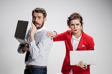 Image showing The young businessman and businesswoman with laptops  communicating on gray background