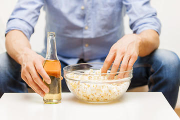 Image showing close up of man with popcorn and beer at home