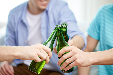 Image showing close up of male friends drinking beer at home