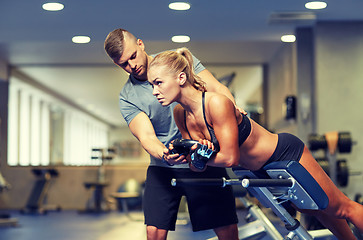 Image showing woman with personal trainer flexing muscles in gym