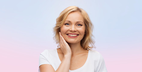 Image showing smiling woman in white t-shirt touching her face