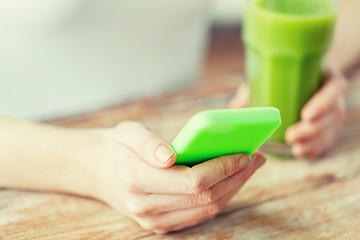 Image showing close up of woman with smartphone and green juice