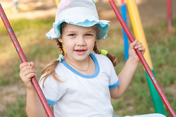 Image showing Five-year girl in summer panama rides on a swing