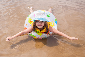 Image showing  Little girl in the shallows lying on his stomach in the inflatable ring outstretched arms and legs