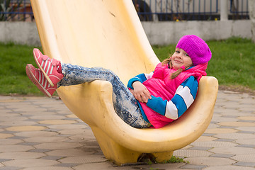 Image showing Five-year girl moved down from the hill sits cheerfully on it