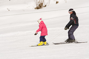 Image showing Dombay, Russia - February 7, 2015: A man learns to ski teenage girl on a snow-covered slope ski resort Dombai