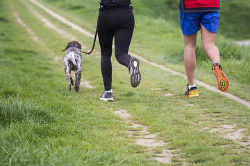 Image showing Young man and woman running with dog