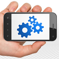 Image showing Business concept: Hand Holding Smartphone with Gears on display